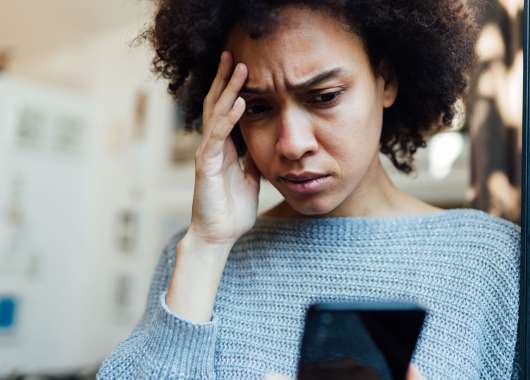 Image of a person looking at their phone with a worried expression