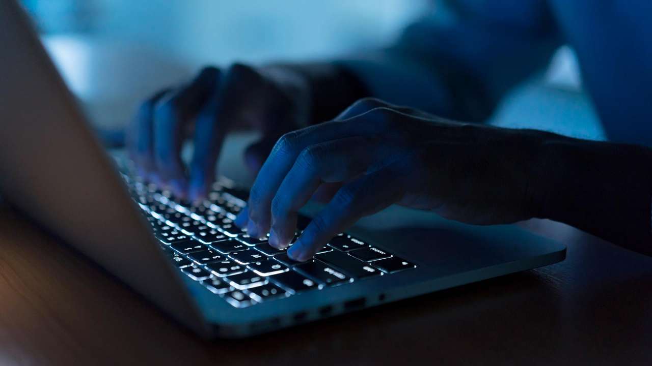 A figure of a dark web surfer using a laptop to access the dark web.