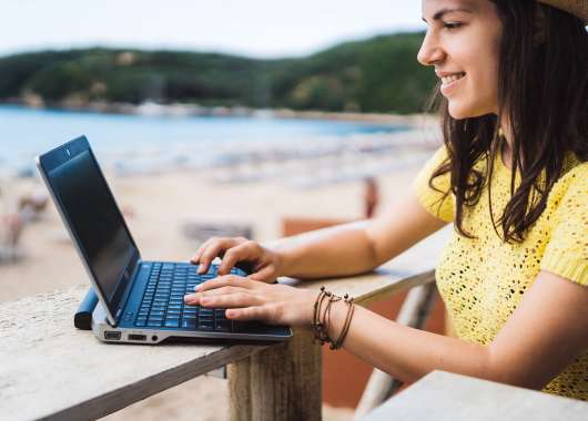 girl working on computer by a beach