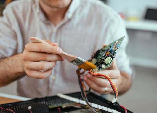 A person trying to clean their PC hard drive with a brush.