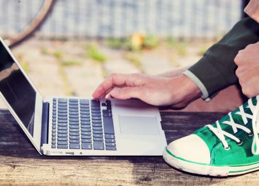 A person kneeling while using their laptop
