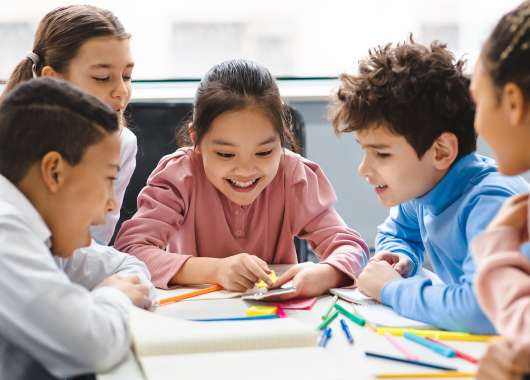 School kids learning over a table looking at a smartphone.