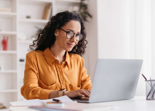 Woman sitting at a desk and typing on a laptop.