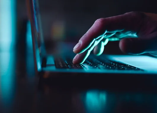 A man’s hand browsing on a laptop.