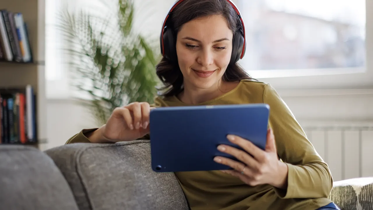 Woman sitting on a couch watching something on her tablet