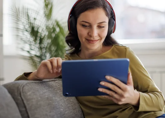 Woman sitting on a couch watching something on her tablet