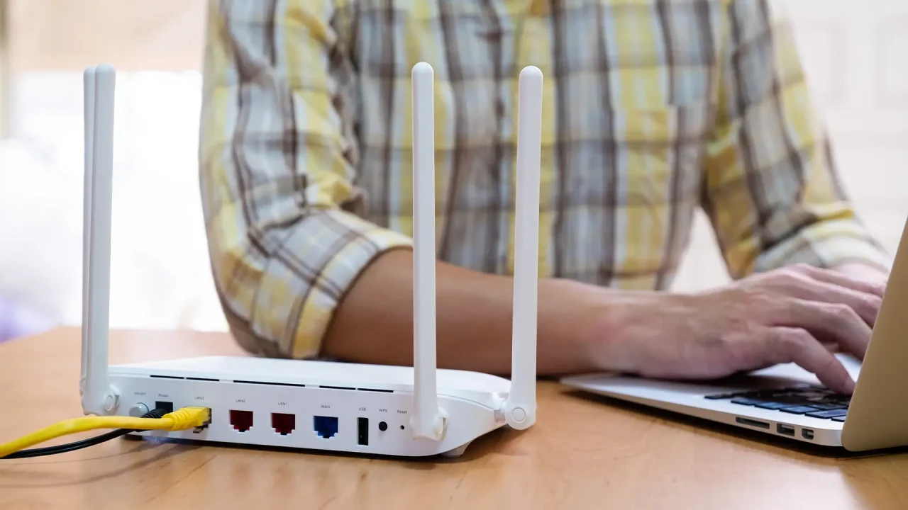 a cropped photo of a person in a plaid shirt changing their IP address on a laptop