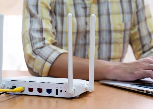 a cropped photo of a person in a plaid shirt changing their IP address on a laptop