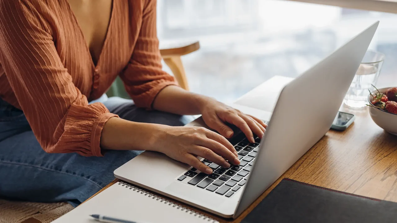 A young professional works on their laptop in a coffee shop.