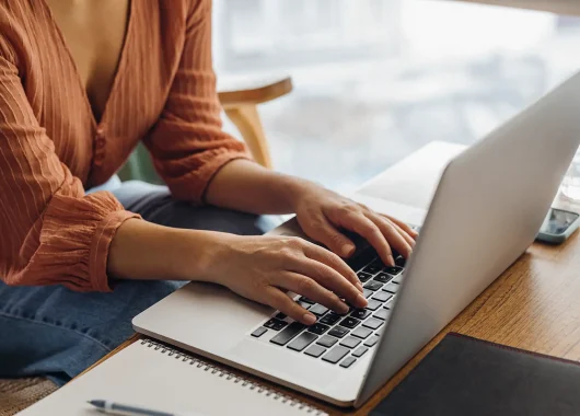 A young professional works on their laptop in a coffee shop.